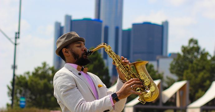 Der Musiker Saxappeal spielt Saxophon mit einem Hut und der Bellis Holzfliege